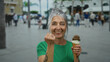 © Krakenimages.com - Senior woman with grey hair happily enjoys ice cream on a busy street, embodying joy and savoring life outdoors with vibrant city life bustling around her.
