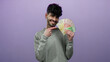 © Krakenimages.com - Smiling man holding fan of norwegian krone banknotes against purple background symbolizing wealth success and prosperity in modern scandinavian setting.