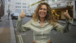 © Krakenimages.com - Woman showing thumbs up gesture on street, smiling with visible hands and cropped shirt midriff; joy confidence.