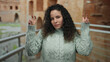 © Krakenimages.com - Woman gesturing playfully at roman ruins background in outdoor setting with ancient architecture showcasing a young hispanic female in casual attire.