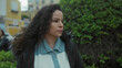 © Krakenimages.com - Woman standing outdoors in a park with a serious expression, wearing a winter jacket in an urban setting, trees and buildings visible in the background.