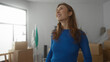 © Krakenimages.com - Young woman smiling in a bright new apartment with moving boxes around suggesting a fresh start in a new home and feeling content with her new living space.