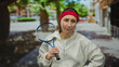 © Krakenimages.com - Woman holding tennis racket looking thoughtful in a city street background, wearing a red headband and white sweatshirt, portraying outdoor tennis sport and expression.