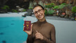 © Krakenimages.com - Woman holding thai passport at a resort pool, smiling with joy, emphasizing vacation anticipation and travel readiness in an outdoor hotel setting.