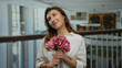 © Krakenimages.com - Woman smiling indoors holding flowers in a well-lit hotel setting wearing a white shirt showcasing a happy and relaxed atmosphere with a hint of elegance and simplicity.