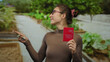 © Krakenimages.com - Young woman in park holding swiss passport with happy expression and glasses, pointing with index finger amid lush greenery outdoors on a sunny day, showcasing travel concept