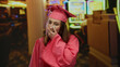 © Krakenimages.com - Young woman in pink graduation gown surprised at casino slot machine background, suggesting unexpected celebration or fortune.
