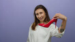 © Krakenimages.com - Woman holding red high heel shoe against isolated purple background, showcasing fashionable style with a playful expression, wearing white shirt and displaying tattoo on arm.