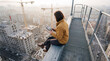 © Rendara Studio - Woman observing urban construction from a rooftop walkway while holding a tablet