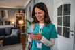 © Migma_Agency - Healthcare professional smiling and using mobile phone during home visit