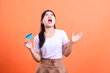 © Ajab - A young woman looking upset while holding a credit card, with an angry and frustrated facial expression, isolated on orange background