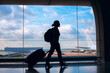 © Song_about_summer - airport, silhouette of woman passenger walking with luggage to take flight in modern airport