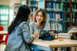 © Wanwajee - Professional women reviewing information on tablet at library desk with books showing knowledge driven collaboration work culture