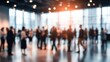 © datronis - Energetic Blurred Crowd in Modern Convention Hall Bathed in Warm Sun Flare.