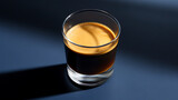 A captivating close-up of coffee in a transparent glass. The dark liquid and frothy layer create a visually stunning effect, enhanced by dramatic shadows. The glass has a simple design.