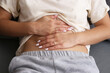 © Paweł Michałowski - Woman lying on sofa holding lower abdomen with hands. Menstrual pain and period cramps concept. Female health problem. Stomach ache during menstruation. Monthly cycle discomfort and pain.