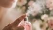 © Pupan - Close-up of a person spraying a delicate pink perfume bottle, creating a fine mist against a soft floral background.