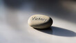 © photo for everything - The inscription “Victory” on the stone is a reminder of triumph and accomplishment. The stone’s smooth surface and warm color adds tranquility and determination.