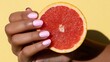 © Katsiaryna - Detailed image of hand showcasing juicy fruit half with glossy polish against vivid backdrop
