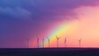 © Kristina - Rainbow sunset appears over windmills in a vast landscape during early evening hours