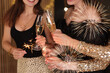© New Africa - Friends with glasses of sparkling wine and sparklers celebrating New Year, closeup
