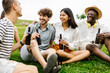 © Xavier Lorenzo - Young group of people enjoying beers while relaxing on grass at city park