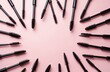 © Pete - Black mascara wands arranged in circle on pink background. These tools are for eyelash, eyebrow grooming, makeup application. They offer volume, definition for polished look. Womens beauty items.