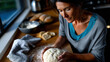 © Milos - A woman attentively kneads dough on a counter, embodying the blend of tradition and modernity in baking, showcasing the tactile pleasure of creating something from scratch.