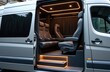 © Viktor - Luxury minibus interior features plush leather seats and ambient lighting. Custom van conversion offers executive travel comfort. Passengers enjoy private, stylish journey inside this modern vehicle.