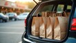 © Maryna - Car trunk packed with paper shopping bags near supermarket. Purchases are loaded for transport home. Groceries, retail goods, and consumer items await a car ride.