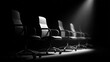 © Nuttawut - Empty Chairs in Spotlight: A row of office chairs in a dark setting, illuminated by a spotlight, hinting at an unspoken presence and anticipation.