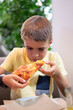 © Arianne - Boy enjoying delicious slice of pizza at restaurant
