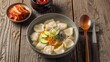 © NYL - A steaming bowl of authentic Korean Sujebi, featuring tender hand-torn dough pieces in a clear, savory broth with anchovies, zucchini, and carrots.