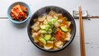 © NYL - A steaming bowl of authentic Korean Sujebi, featuring tender hand-torn dough pieces in a savory broth with zucchini, carrots, and a side of spicy kimchi.