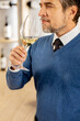 © BGStock72 - Man enjoying white wine while standing in a wine shop during the evening hours