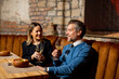 © BGStock72 - Couple enjoys dinner and drinks in modern restaurant setting at night