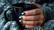 © Oleh - Woman's hand with creative nail art manicure holding a dark black mug, wrapped in a warm grey knitted sweater, representing comfort, coziness, and a relaxing winter morning at home