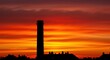 © Rafal Rut - Spectacular sunset view of industrial cityscape with silhouette of a tall chimney.