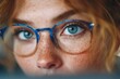 © Fat Bee - Close-up of blue glasses reflecting an office worker with vibrant blue eyes and freckles