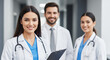 © abu - Three smiling doctors in white coats with stethoscopes in a hospital hallway, showcasing a medical team and healthcare collaboration with a focus on health and wellness.