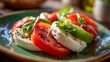 © adnan - Close up of caprese salad with tomatoes mozzarella and basil on a green ceramic plate