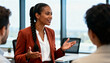 © SERHII - Confident Black businesswoman speaking during a corporate meeting. Female leader explaining a project to colleagues in a modern office.