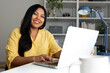 © Daniel - Latin american woman working from home using laptop computer smiling at camera