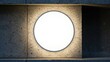 © Nonot - Circular illuminated disk on dark industrial wall at night.