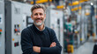 © Sabana - A middle-aged man with a friendly smile standing in front of industrial machinery with his arms crossed in a factory setting
