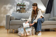 © GRAFStock - Young woman sits on sofa packing baby clothes into transparent bag, preparing for hospital visit or travel