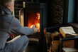 © Home-stock - Man throwing wood into stove in cozy room, firewood burning brightly, heating house in cold season