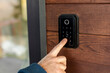 © Home-stock - Male hand pressing button on keypad at entrance to unlock door mounted on wooden wall, keypad has numbers