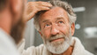 © Ruzana - Elderly man inspecting hair for hair loss diagnosis and treatment consideration