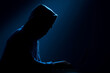 © lashkhidzetim - A man is sitting in front of a laptop with a hood over his head